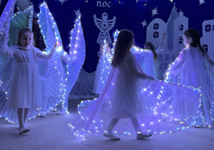 Dziewczynki tańczą taniec aniołów z podświetlanymi skrzydłami.