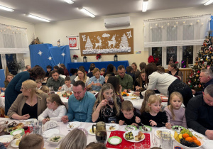 Dzieci spożywają z bliskimi kolację wigilijną.