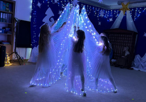 Aniołki tańczą z podświetlanymi skrzydłami.