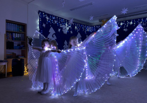 Dziewczynki tańczą ze świecącymi skrzydłami.