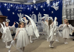 Dziewczynki jako aniołki tańczą z szarfami.