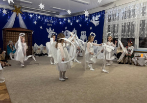 Dziewczynki tańczą z białymi szarfami.