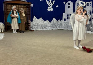 Dziewczynka śpiewa do mikrofonu pastorałkę.