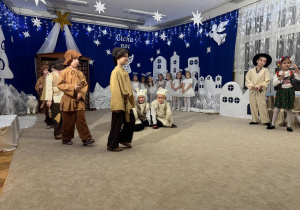 Pasterze i owieczki śpiewają i grają na instrumentach.