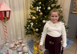 Dziewczynka stoi koło choinki.