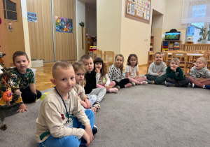 Dzieci siedzą w kole i słuchają opowiadania.