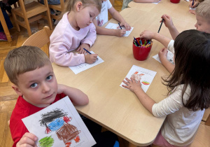 Chłopiec pokazuje pokolorowaną postać Nudka.