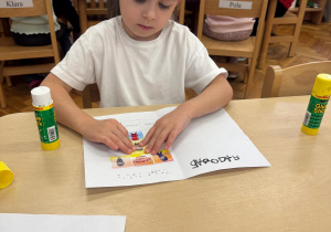 Dziewczynka wkleja postać Nudka do książeczki.