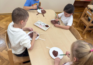 Dzieci malują papierowe talerzyki.