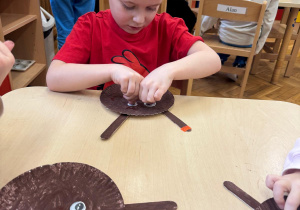 Chłopiec przykleja oczy renifera.