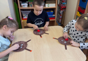 Dzieci przyklejają nos reniferowi.