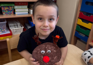 Chłopiec pozuje z wykonanym przez siebie reniferem.