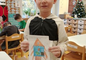 Chłopiec prezentuje swój rysunek.