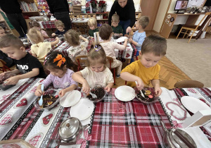 Dzieci nabierają herbatę na łyżeczkę.