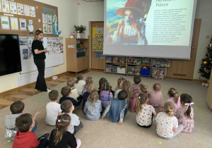 Dzieci słuchają i oglądają prezentację o historii herbaty.