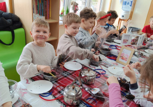Dzieci wsypują susz herbaciany do torebeczek.