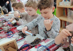 Dzieci wsypują susz herbaciany do torebeczek.