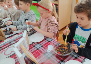 Dzieci wsypują susz herbaciany do torebeczek.