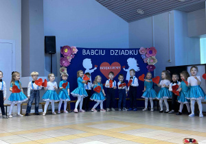 Dzieci trzymają serca w dłoni i śpiewają.