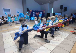 Chłopcy grają na gitarach, dziewczynki tańczą.
