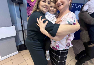Babcie trzymają wnuka na rękach.