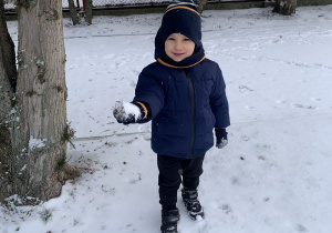 Chłopiec lepi ze śniegu kulkę.