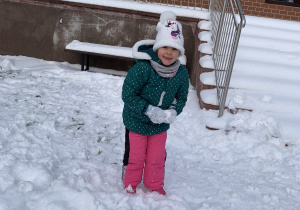 Dziewczynka robi kulkę ze śniegu.