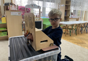 Chłopiec poprzez dotyk odgaduje co ma ze skrzyni pomysłów.