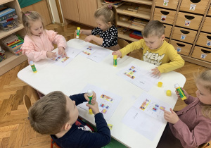 Dzieci wklejają Nudka do książeczki.