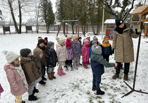 Czterolatki przygladają się gdzie należy sypać ziarenka.