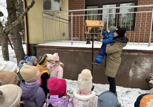 Chłopiec wsypuje do karmnika ziarenka.