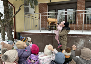 Dziewczynka wsypuje pokarm do karmnika.