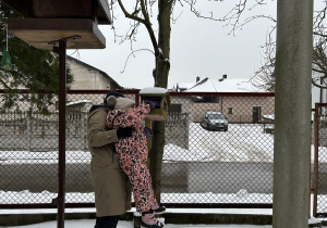 Dzieci wsypują ziarenka do kolejnego karmnika znajdującego się w ogrodzie przedszkola.