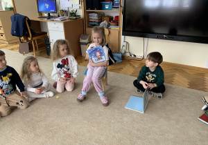 Dziewczynka prezentuje książkę - Kicia Kocia.