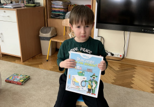 Chłopiec prezentuje książkę z zakresu techniki.