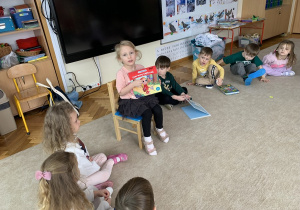 Dziewczynka pokazuje swoją ulubioną książkę innym dzieciom.