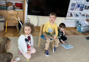 Chłopiec opowiada o dinozaurach pokazując ilustracje ze swojej książki.