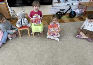 Dziewczynka pokazuje dzieciom swoją ulubioną książkę.