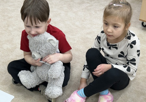 Czterolatki witają się z misiem Karolkiem.