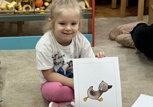 Dziewczynka prezentuje ilustracje z bajki Brzydkie Kaczątko.