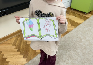 Dziewczynka pokazuje swój rysunek.