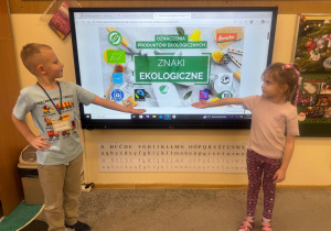 Dzieci pokazują jak wyglądają znaki, którymi są oznaczone produkty ekologiczne.