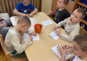 Chłopcy siedzą przy stoliku i kolorują Brawojkę.