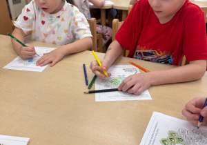 Chłopiec z dziewczynką kolorują pawia.