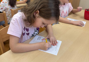 Dziewczynka koloruje pawia.