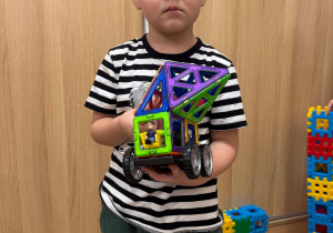 Chłopiec pokazuje zbudowany przez siebie samochód.