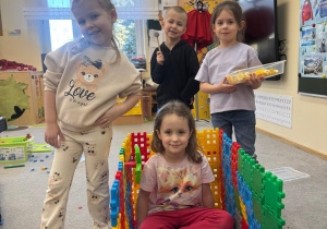 Dzieci pozują wspólnie przy swojej budowli z klocków.