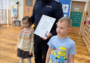 Dzieci stoją z panem policjantem.