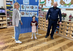 Dziewczynka stoi obok tablicy z zasadami bezpieczeństwa.