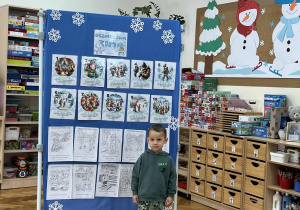 Chłopiec stoi obok tablicy z zasadami.